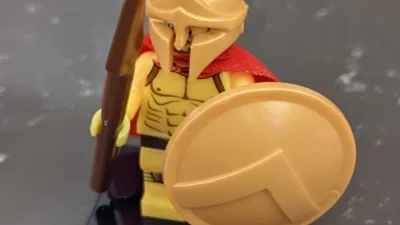 A lego spartan soldier holding a spear and shield.